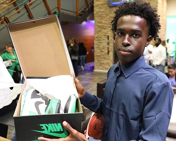 一个年轻人拿着盒子里的新鞋摆姿势拍照